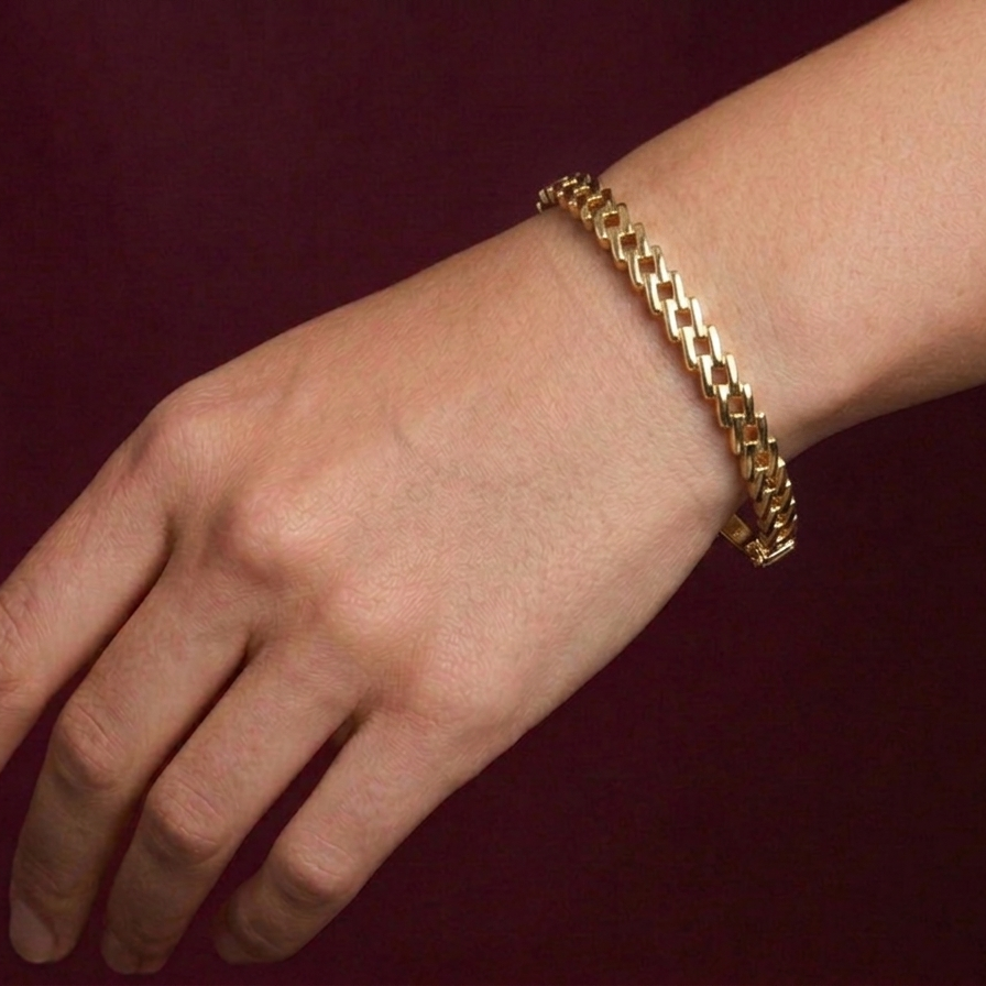 Gold bracelet on a wrist against a dark background