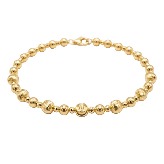 Gold beaded bracelet on a white background