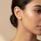 Close-up of a woman wearing a gold heart-shaped stud earring, fine jewelry detail