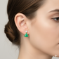 Woman wearing a green gemstone gold earring with diamond accent, close-up view