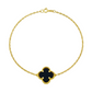 Gold bracelet with a black clover-shaped charm on a white background