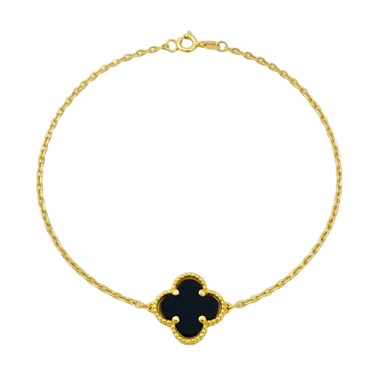 Gold bracelet with a black clover-shaped charm on a white background