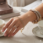 Hand with gold bracelets and ring on a table with tea cups