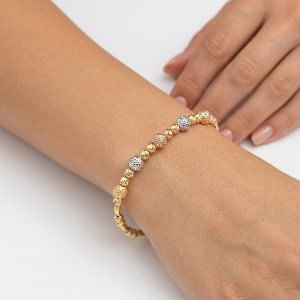 Gold and silver beaded bracelet on a wrist with a white background