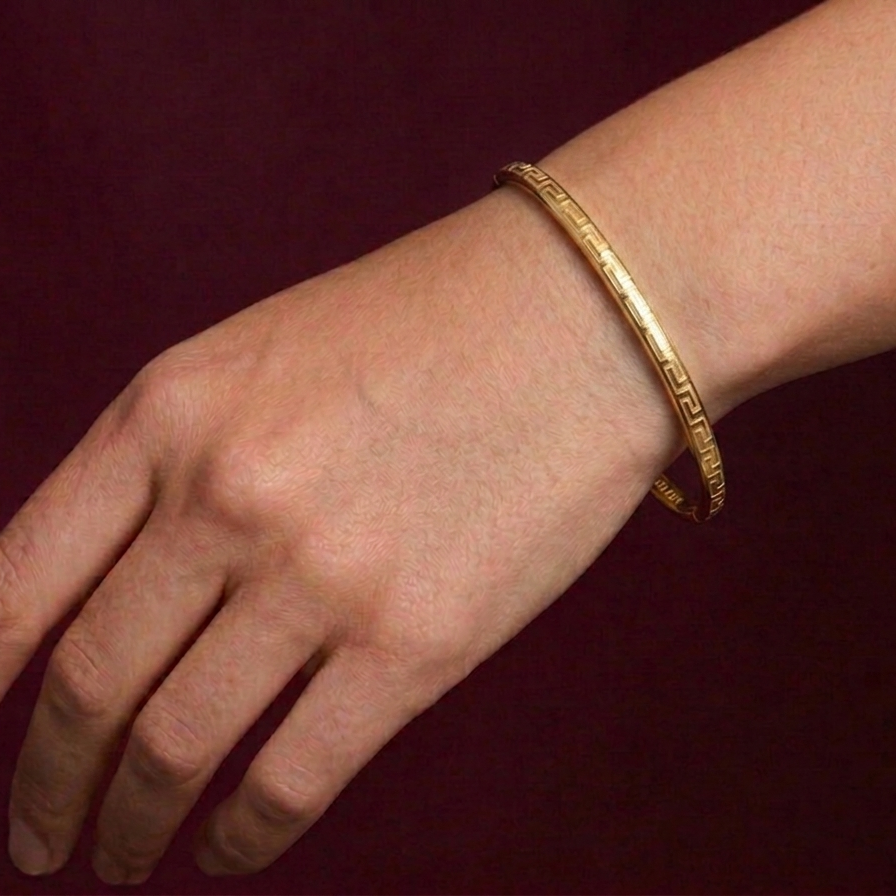 Gold bracelet on a wrist against a dark background