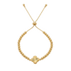 Gold beaded bracelet with a clover-shaped charm on a white background