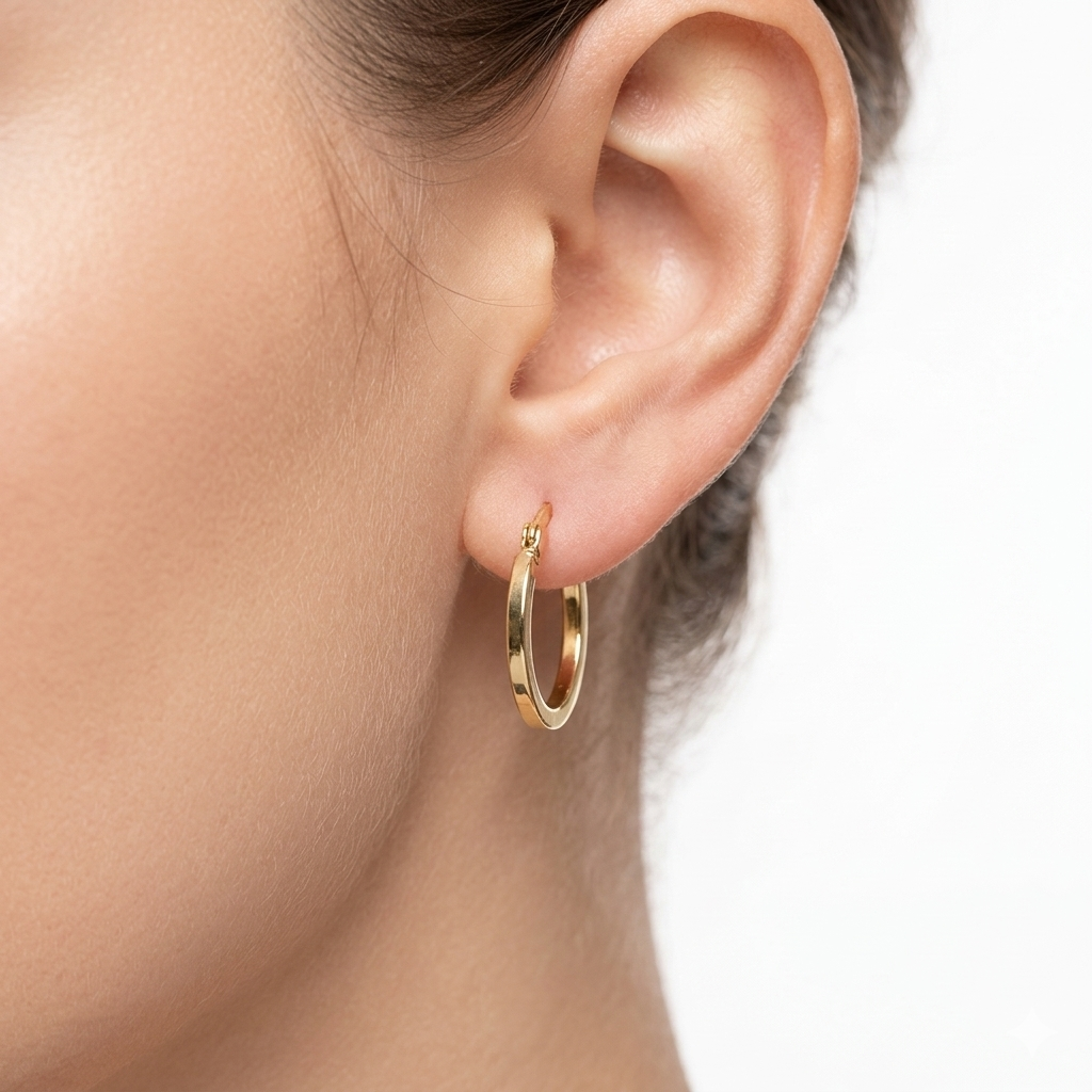 Gold hoop earring worn by a person on a neutral background
