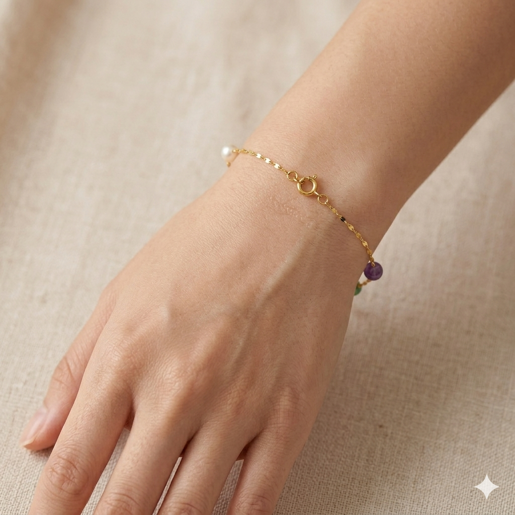Gold bracelet with a purple bead on a hand against a beige background