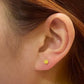 Close-up of ear wearing a round yellow gold stud earring