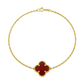 Gold bracelet with a red clover-shaped charm on a white background
