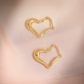 Gold heart-shaped hoop earrings on a pink satin background