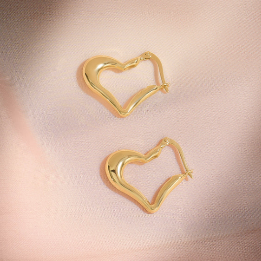 Gold heart-shaped hoop earrings on a pink satin background