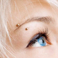 Close-up of a person with blonde hair and blue eyes wearing gold earrings.