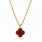 Gold necklace with a red clover-shaped pendant on a white background