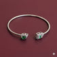 Silver bracelet with green gemstones on a maroon background