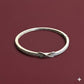 Silver bracelet with small stones on a maroon background