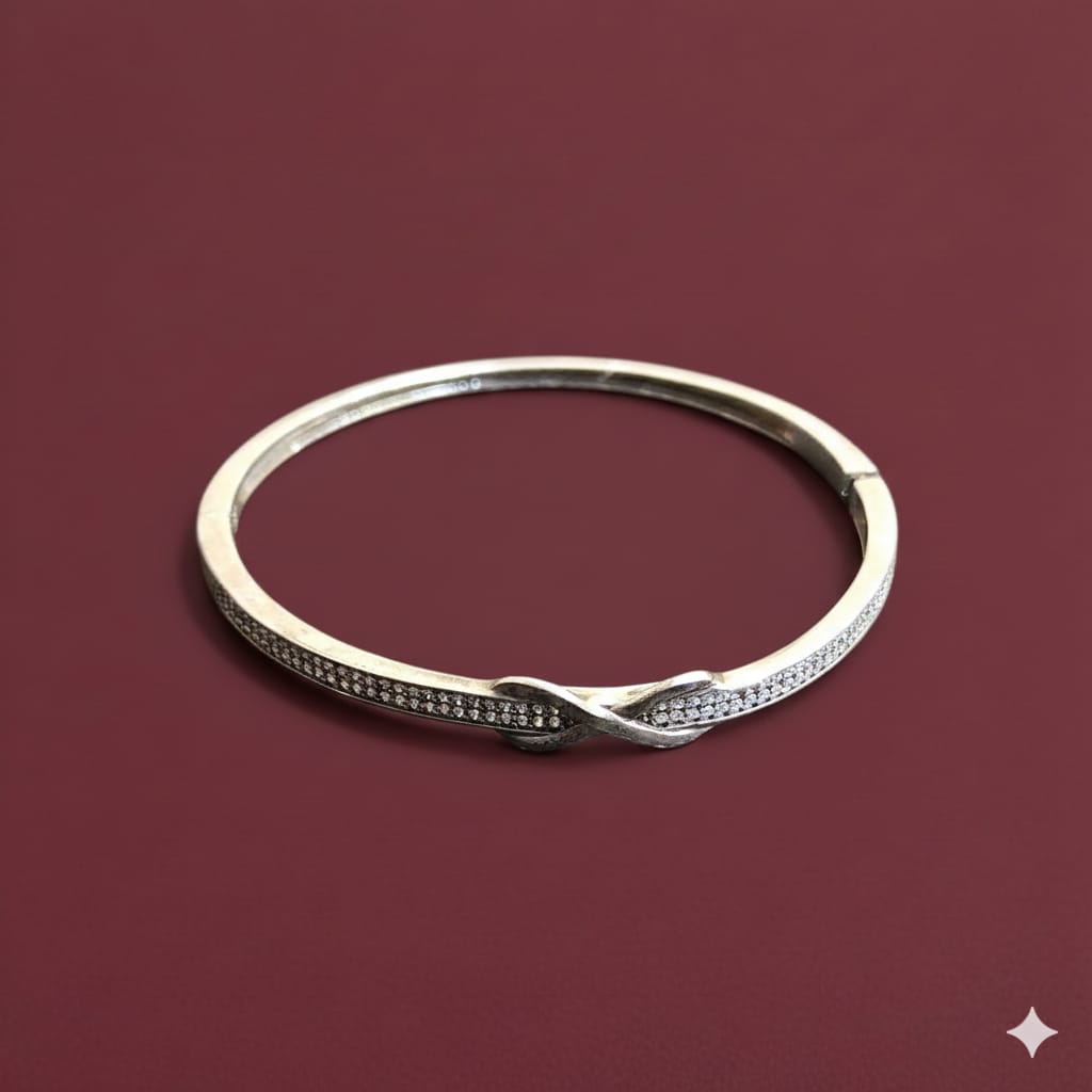 Silver bracelet with small stones on a maroon background
