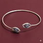 Silver bracelet with eye-shaped charms on a maroon background