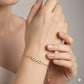 Gold bracelet with an infinity symbol on a maroon background