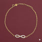 Gold bracelet with heart charm on wrist against a neutral background