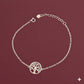 Silver bracelet with a tree of life design on a maroon background