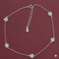 Silver anklet with heart-shaped charms on a maroon background