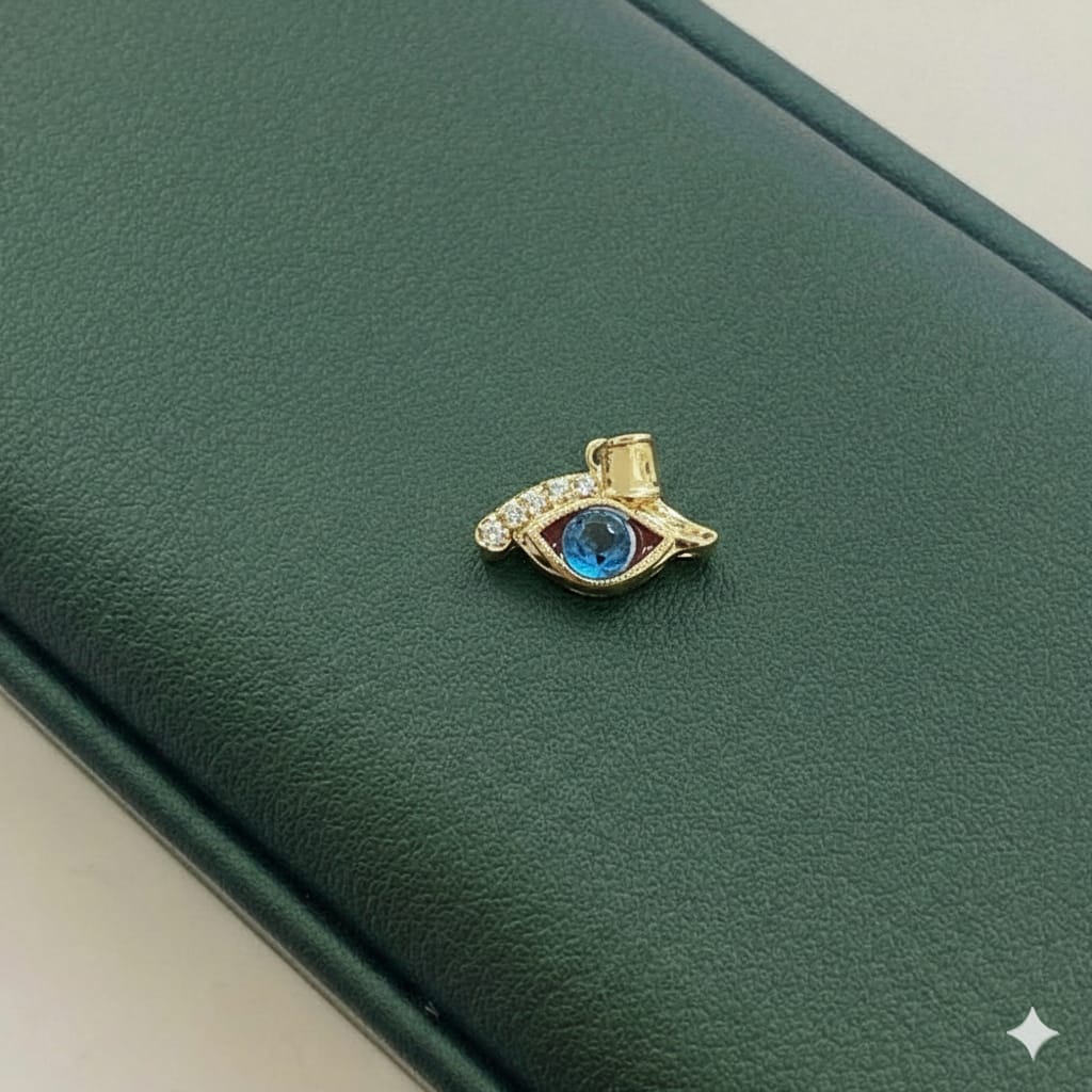 Gold eye-shaped brooch with blue gemstone on a green leather surface
