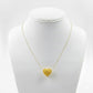Gold heart-shaped pendant necklace on a mannequin bust against a white background