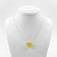 Yellow heart-shaped pendant on a gold chain displayed on a mannequin bust.