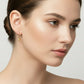 Gold hoop earrings with spherical ends on a gray background