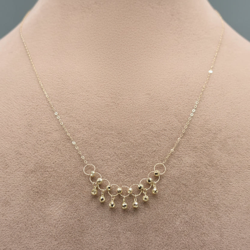 Gold necklace with small beads on a mannequin, close-up inset showing necklace details.