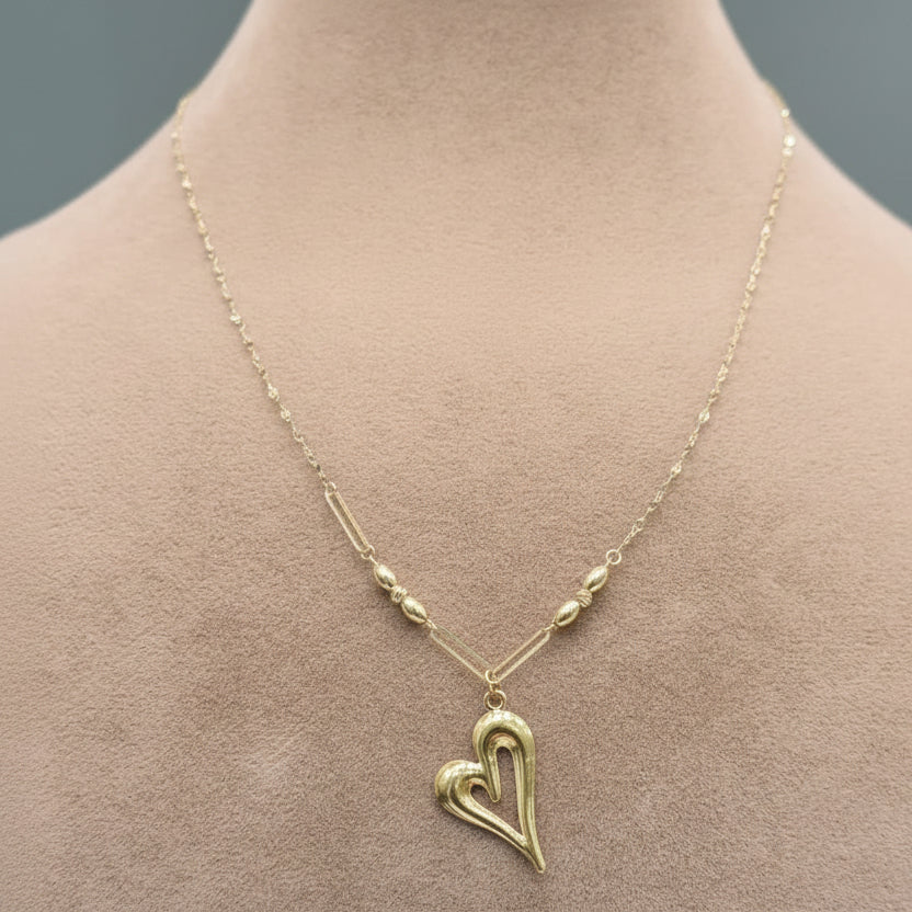 Gold heart-shaped necklace on a mannequin with a neutral background