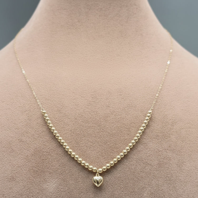 Gold necklace with a heart pendant on a mannequin neck.