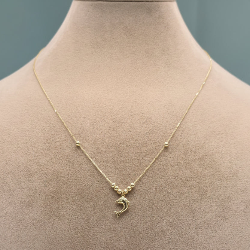 Gold necklace with a pendant on a mannequin bust against a neutral background
