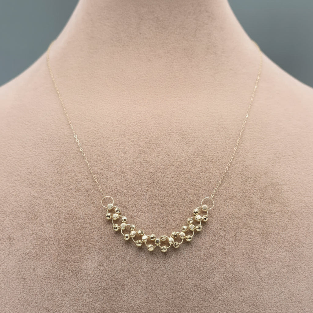 Gold necklace on a mannequin neck against a neutral background