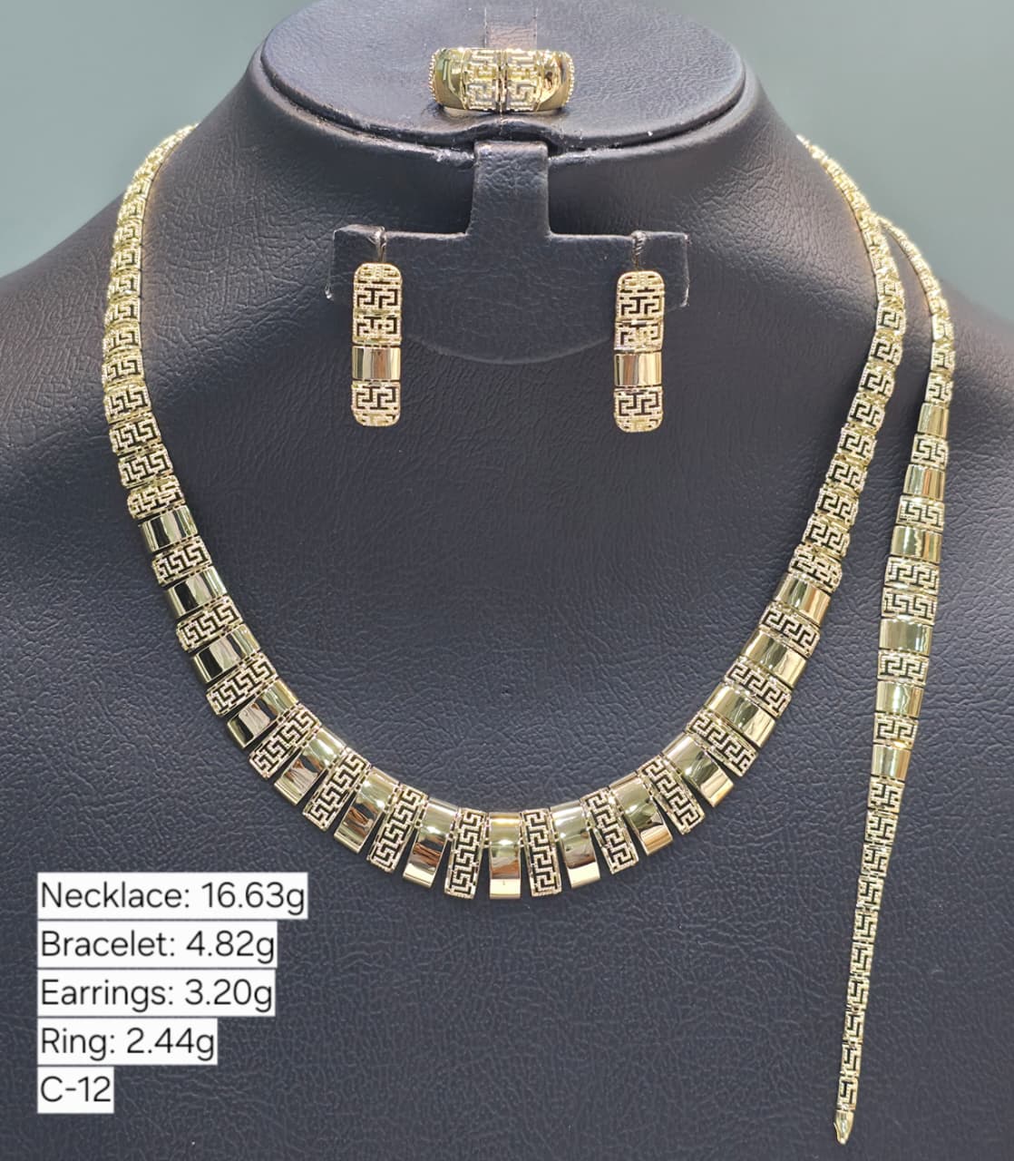 Gold necklace, bracelet, earrings, and ring on a black mannequin with weight information displayed.