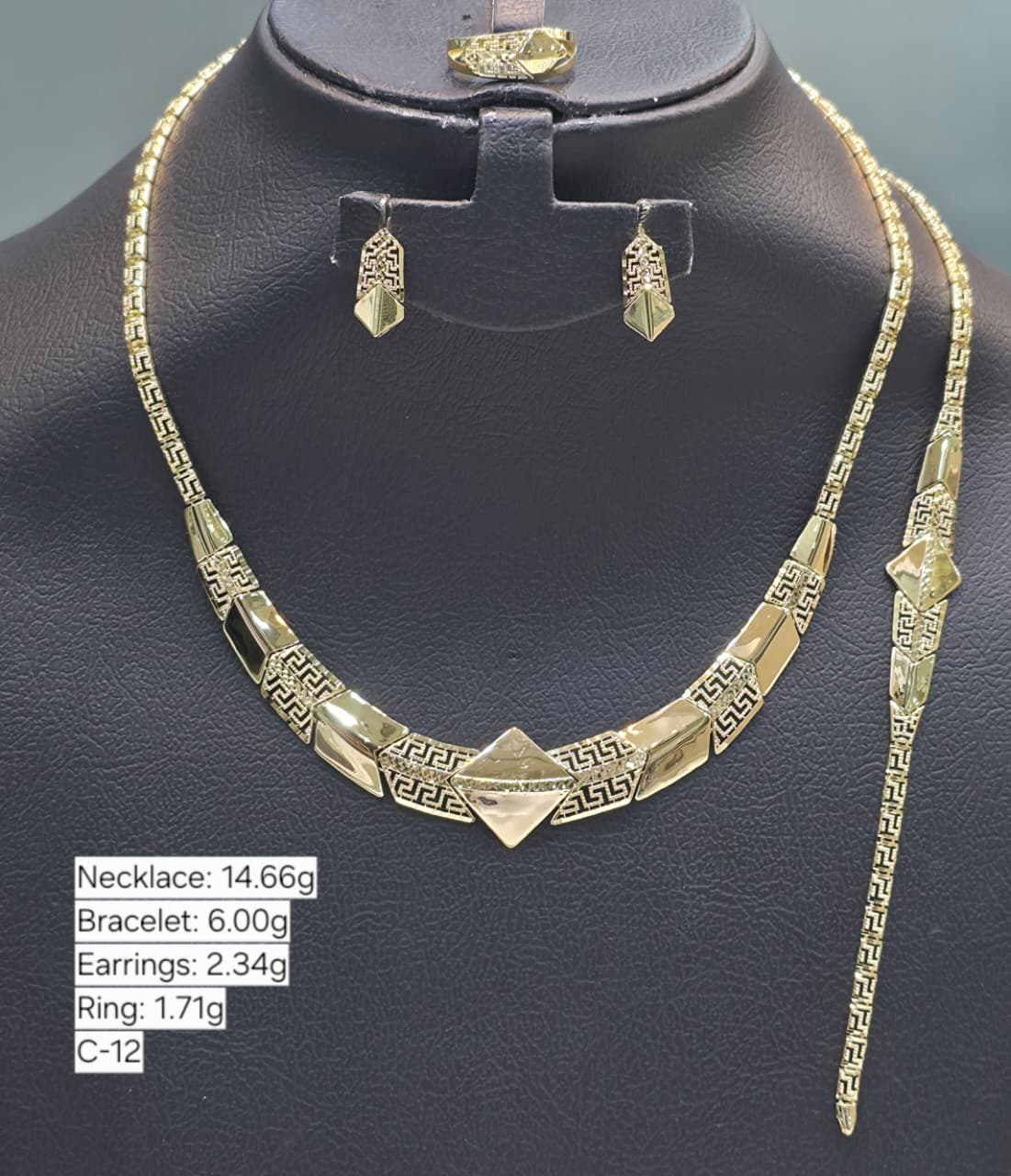 Gold necklace, bracelet, earrings, and ring on a black stand with weight details.