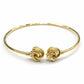 Gold bracelet with intricate design on a gray background
