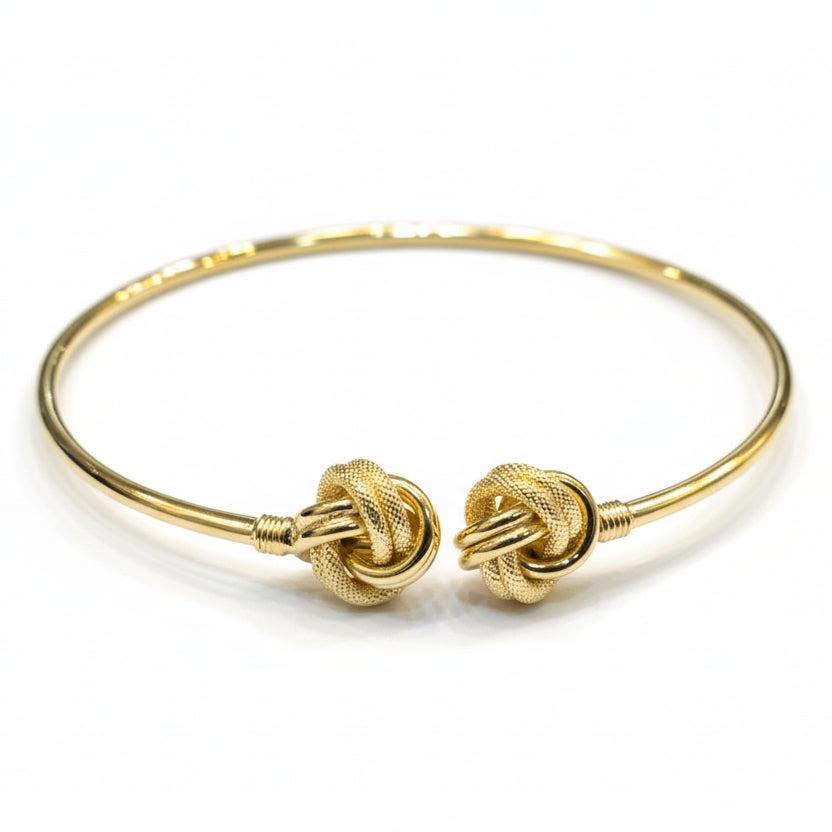 Gold bracelet with intricate design on a gray background