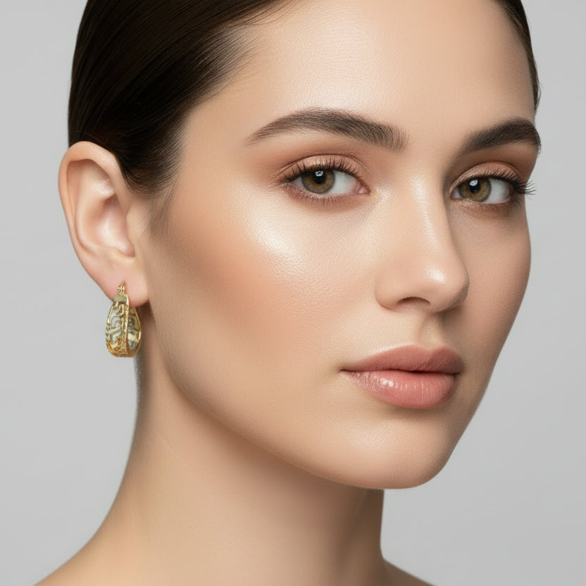 Gold hoop earrings with intricate designs on a white background