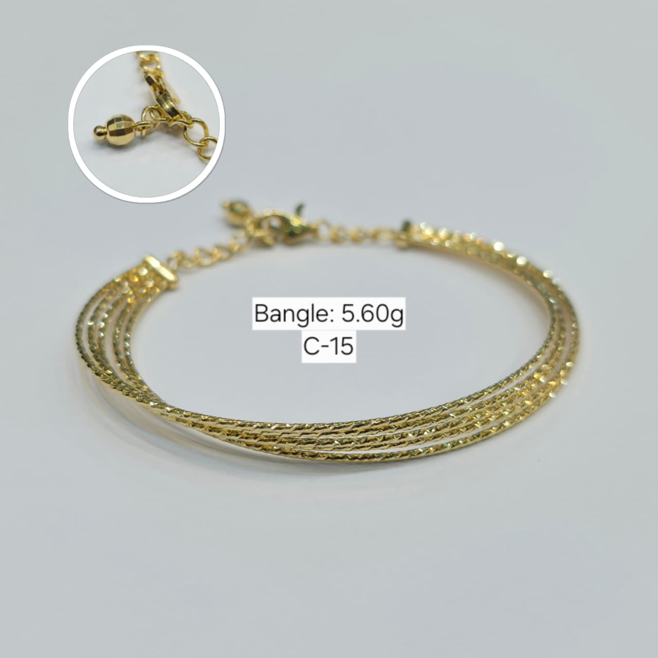 Gold bracelet with chain clasp on a light gray background