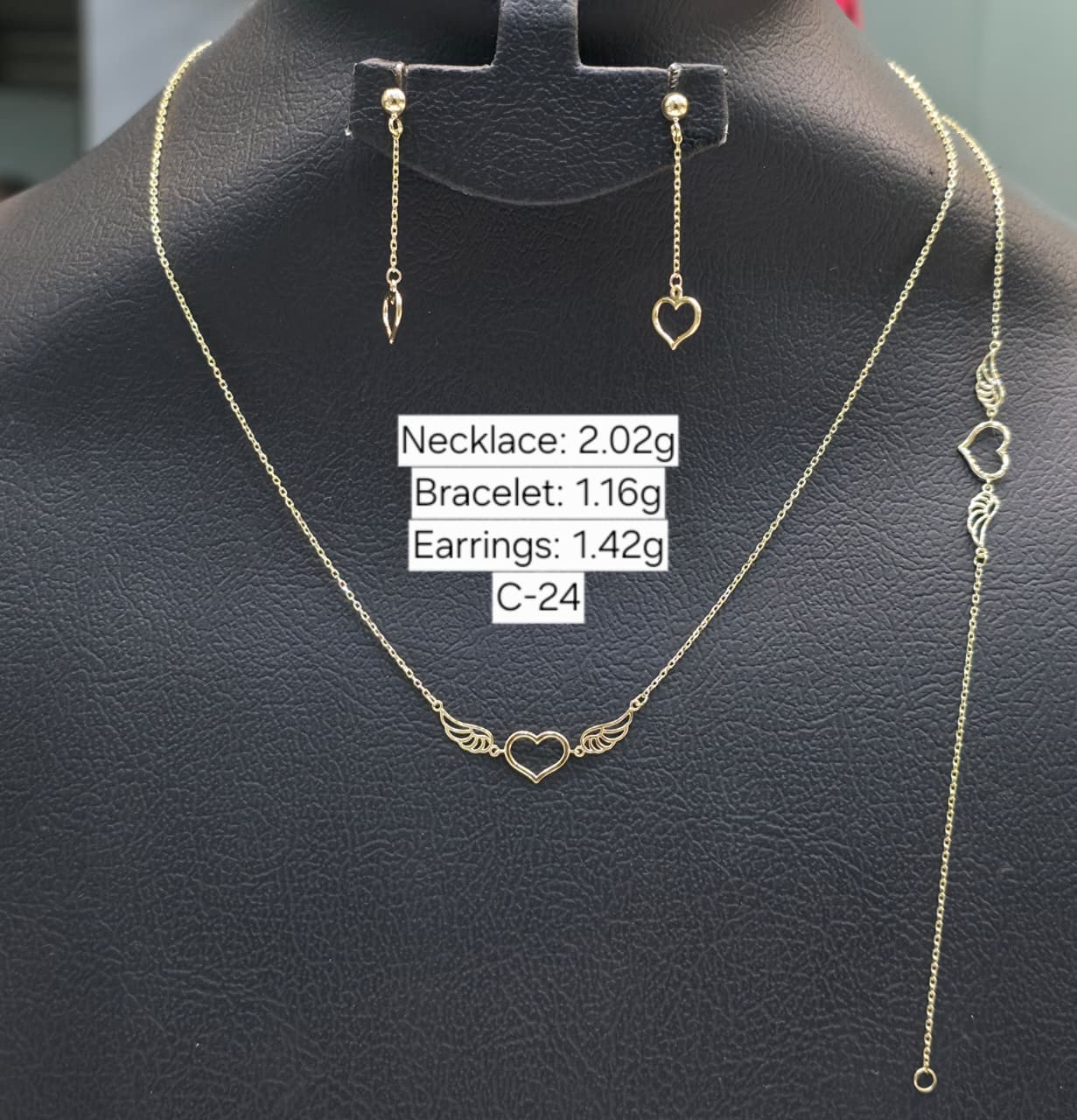 Gold necklace, bracelet, and earrings on a black stand with weight labels.