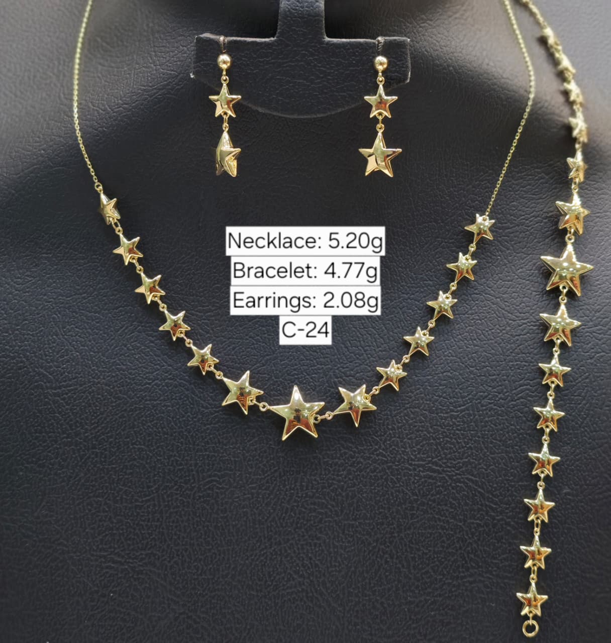 Gold star necklace, bracelet, and earrings on a black stand with weight labels.