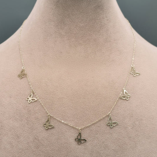 Gold necklace with butterfly pendants on a mannequin neck, labeled with weight and code.