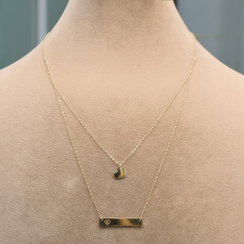 Gold necklace with a heart pendant on a mannequin, displayed against a neutral background.