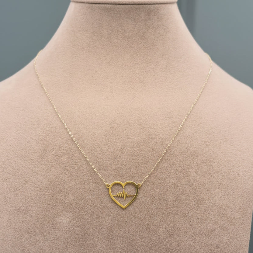 Gold necklace with a heart-shaped pendant on a mannequin.