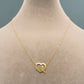 Gold necklace with a heart-shaped pendant on a mannequin.
