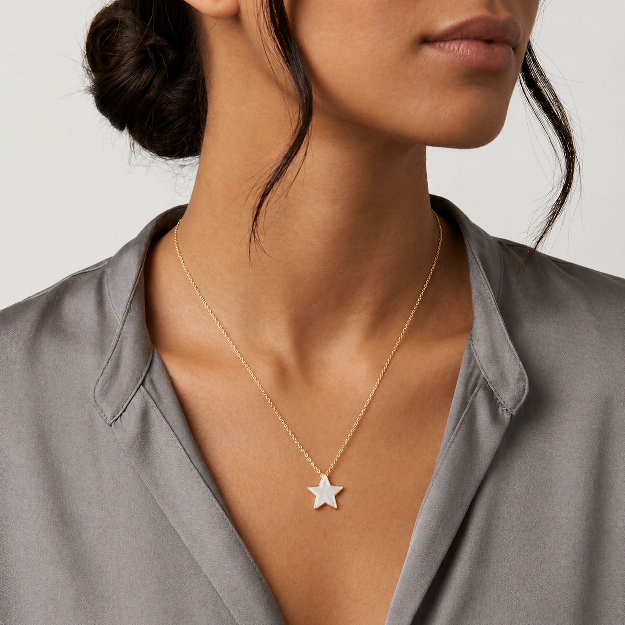 Woman wearing a gold necklace with a star pendant on a neutral background