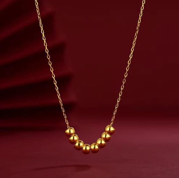 Gold necklace with round beads on a red background