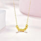Gold necklace with round beads on a light pink background